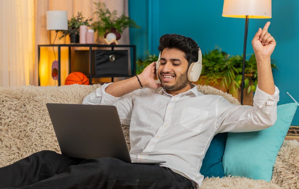 Man relaxing at home with laptop and headphones using Hathway Broadband